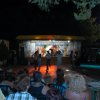 Spettacolo serale all'aperto con pubblico e palco illuminato.