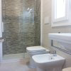 Bagno moderno con doccia, bidet e lavabo, piastrelle a mosaico grigio.