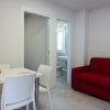Soggiorno con divano rosso, tavolo bianco e vista sul bagno.