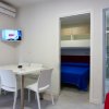 Sala con tavolo bianco, TV, camera da letto blu e bagno.