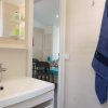 Bagno con lavandino moderno, accappatoio blu appeso e vista su una stanza con tavolo.
